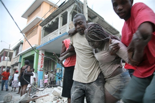 Des hommes viennent en aide à une femme prise dans les décombres d'un immeubles à Port-au-Prince (AFP PHOTO - Lisandro SUERO)