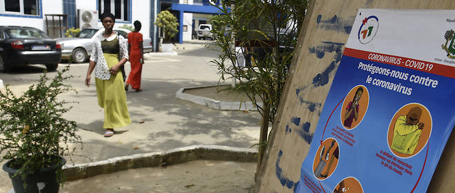 Des passants sont sensibiliss au coronavirus par le biais d'affiches. Ici, elles sont placardes dans la cour d'une glise ferme   Abidjan le 20 mars 
2020